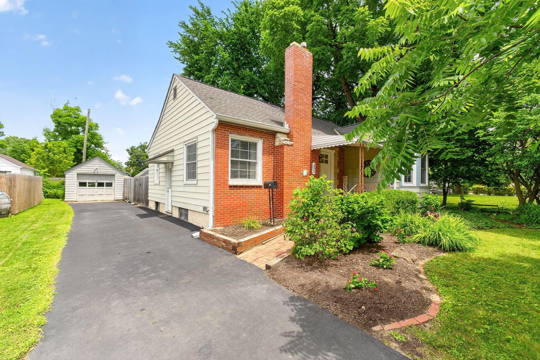 492 Wetmore Road Columbus, OH 43214 - Photo 9 of 55 Single-family residence featuring brick and siding exterior, a prominent brick chimney, and an asphalt driveway leading to a detached garage