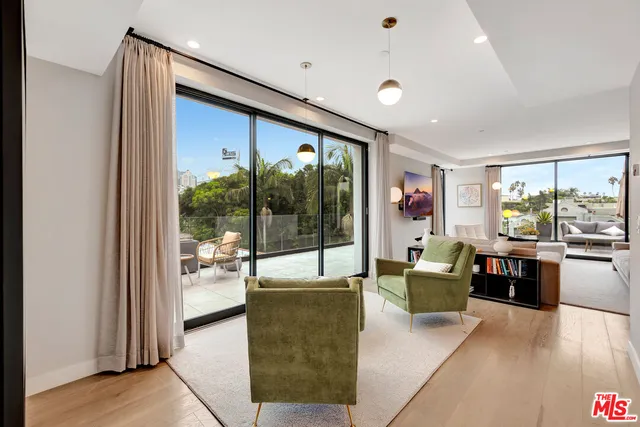 a living room with furniture large window and wooden floor