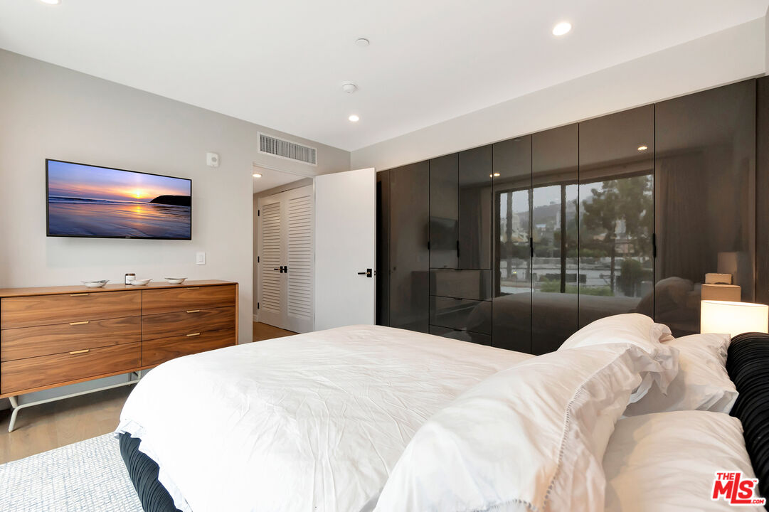 1017 North Croft Avenue, Unit PH1 Los Angeles, CA 90069 - Photo 21 of 34 a bedroom with a large bed and a flat screen tv