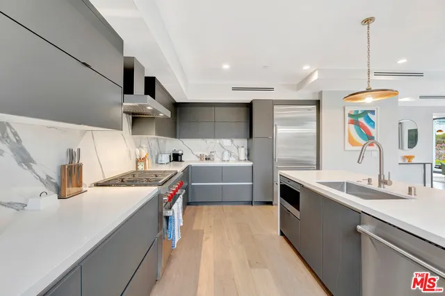 a kitchen with stainless steel appliances a sink a stove a refrigerator and cabinets