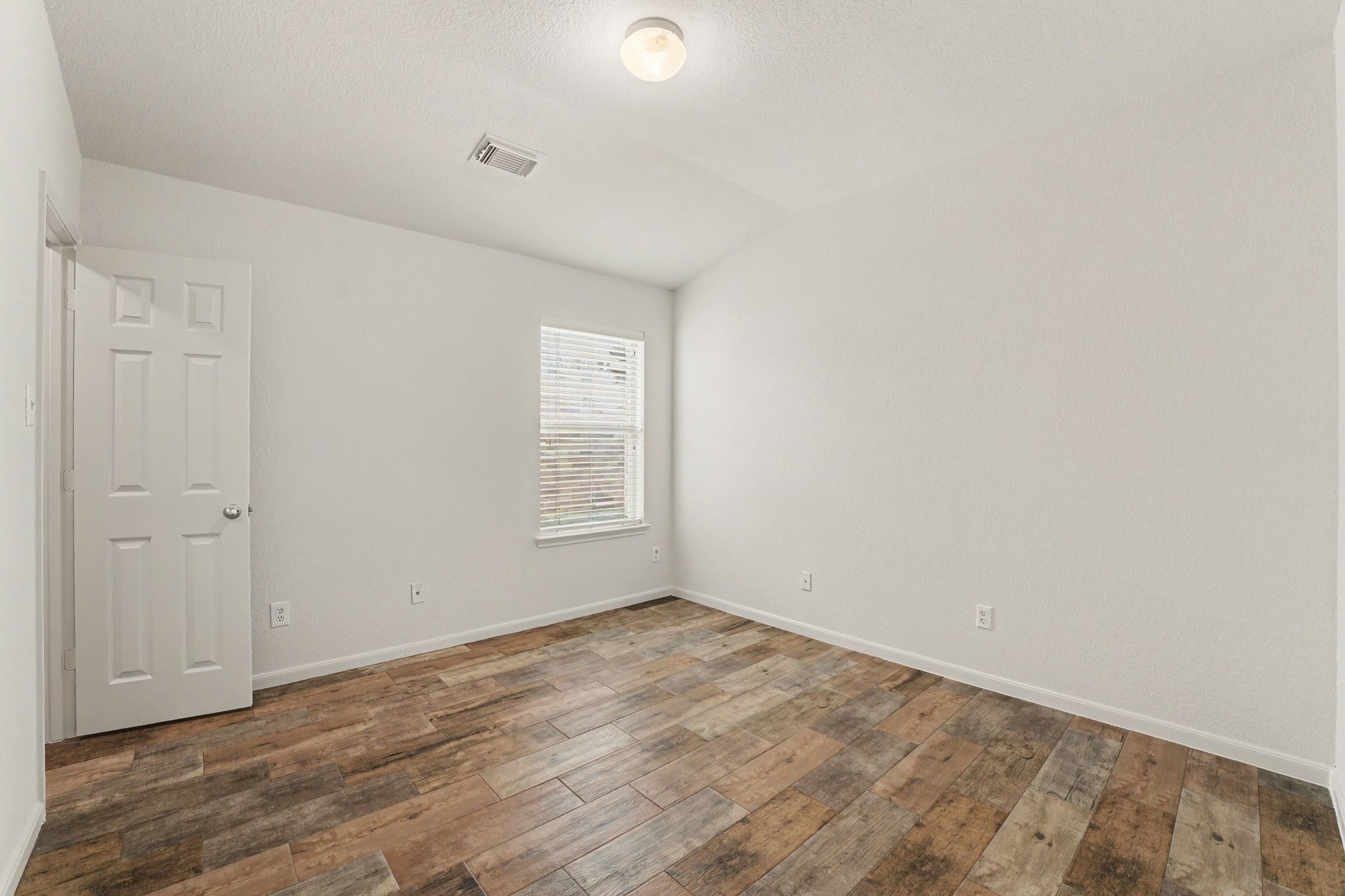 21427 Blooming Rock Lane Spring, TX 77379 - Photo 26 of 32 This room features clean white walls, a single window for natural light, a simple ceiling light, and rustic-style wood flooring.