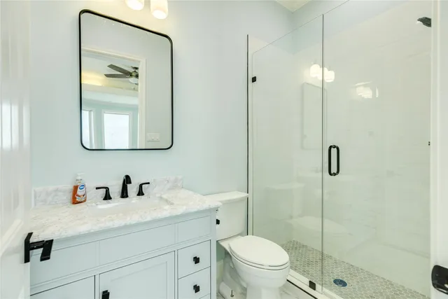 a bathroom with a toilet sink vanity and shower