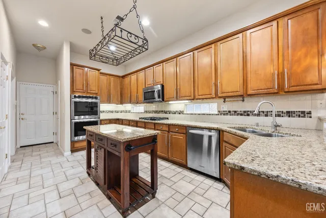 a kitchen with stainless steel appliances granite countertop a sink stove and refrigerator