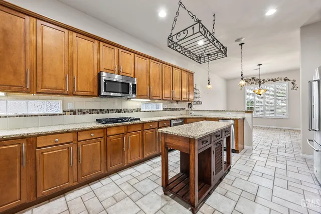 an empty room with chandelier fan and windows