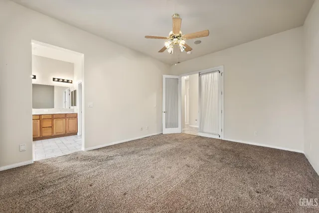 an empty room with a chandelier fan and windows