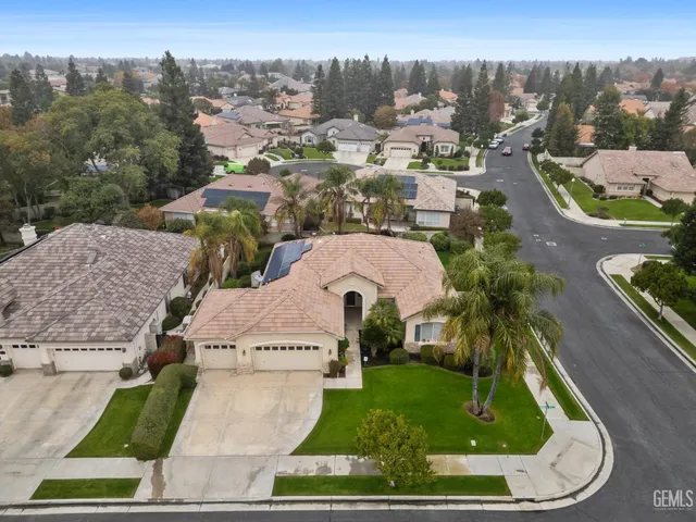 an aerial view of residential houses with outdoor space and trees