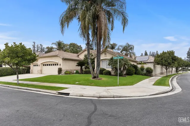 a view of small white house with a big yard and palm trees