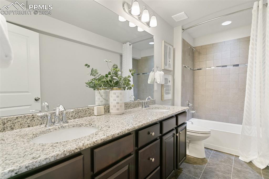 10110 Henman Terrace Peyton, CO 80831 - Photo 26 of 36 a bathroom with a granite countertop sink a toilet a large mirror and shower