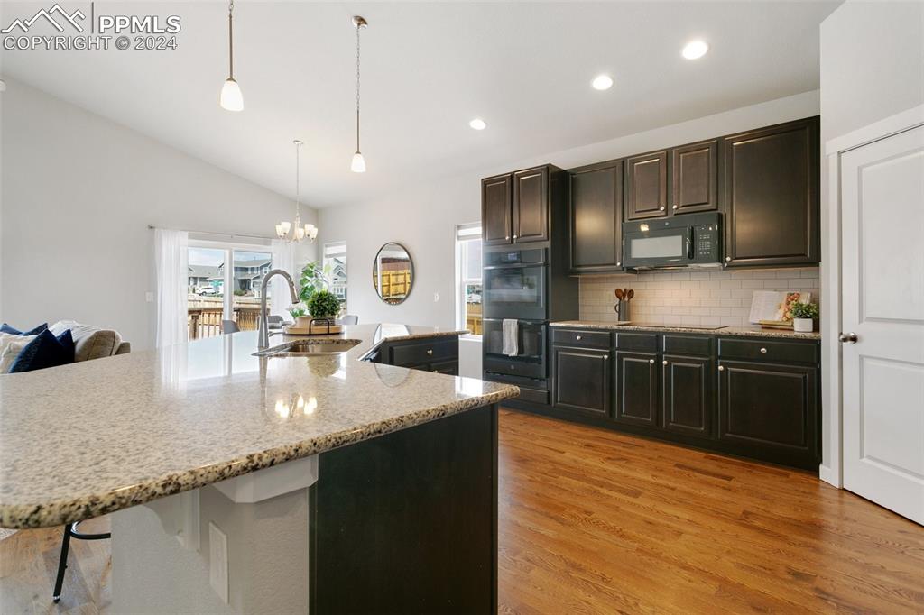 10110 Henman Terrace Peyton, CO 80831 - Photo 10 of 36 a kitchen with stainless steel appliances granite countertop a sink a stove and a wooden floors