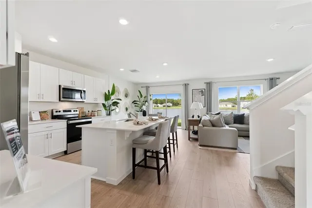a living room with furniture kitchen view and a wooden floor