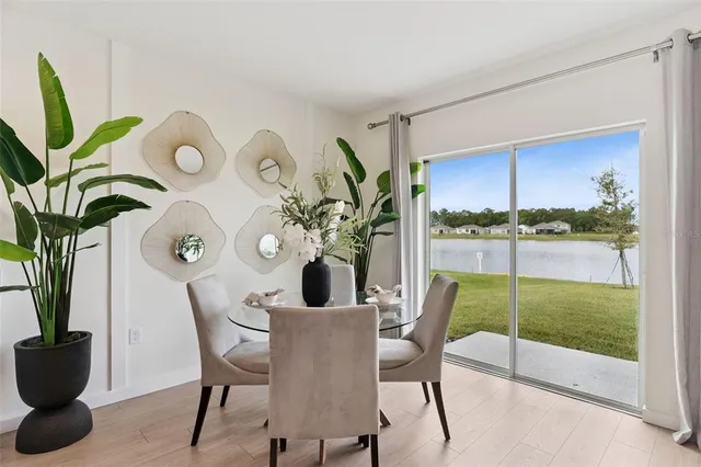 a kitchen with stainless steel appliances a dining table chairs refrigerator and microwave