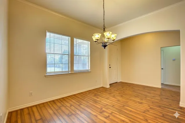 a view of empty room with wooden floor chandelier and window