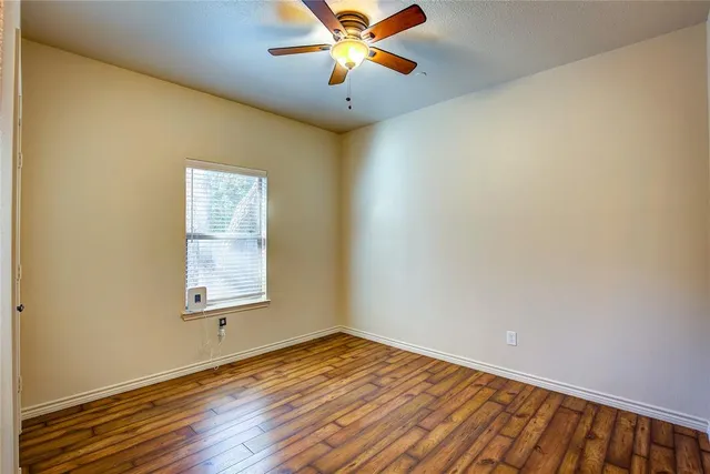 an empty room with a window and a ceiling fan