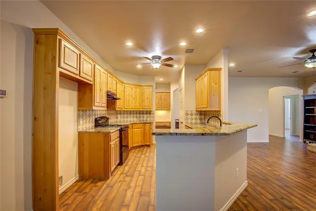 a kitchen with stainless steel appliances granite countertop a sink a stove cabinets and wooden floor