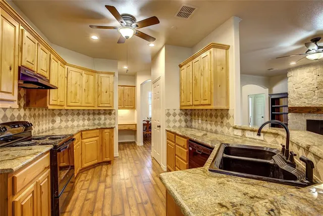 a kitchen with stainless steel appliances granite countertop a sink a stove and a refrigerator