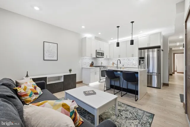a living room with furniture a flat screen tv and kitchen view