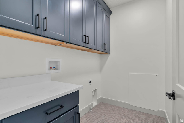 562 West Coyote Rdg Road Grantsville, UT 84029 - Photo 27 of 27 Laundry room featuring dark blue cabinetry with matte black hardware, under-cabinet lighting, a white countertop, and herringbone patterned flooring