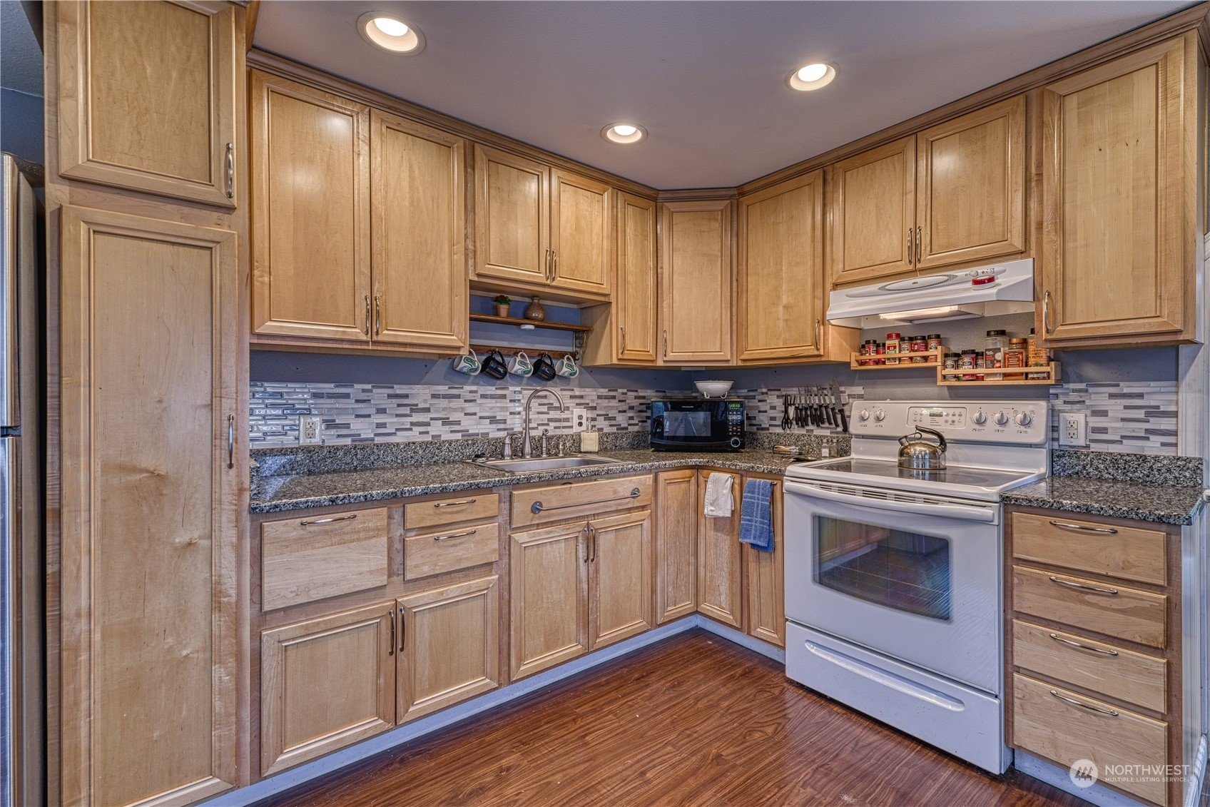 1018 Sheridan Road Bremerton, WA 98310 - Photo 3 of 24 a kitchen with kitchen island granite countertop wooden cabinets and white appliances