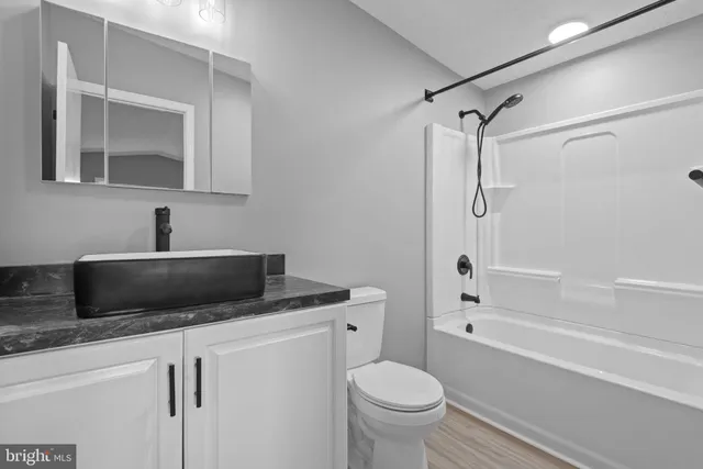a bathroom with a granite countertop sink toilet mirror and bathtub