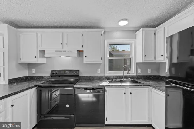 a kitchen with granite countertop a sink a stove and cabinets