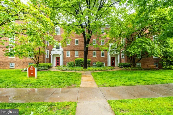 a front view of a building with a garden and trees
