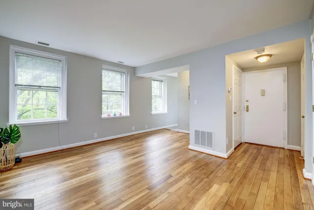 a view of an empty room with wooden floor and a window