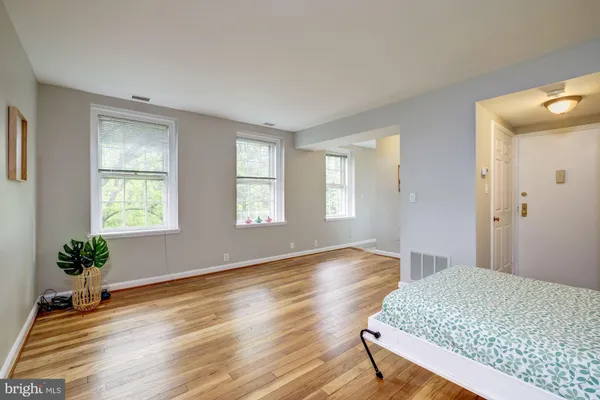 a bedroom with wooden floor and windows