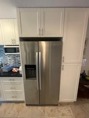 a view of a refrigerator in kitchen and an empty room