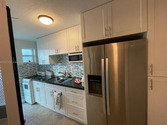a kitchen with stainless steel appliances granite countertop a refrigerator and a stove