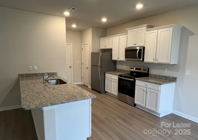 a kitchen with stainless steel appliances granite countertop a refrigerator stove microwave and sink