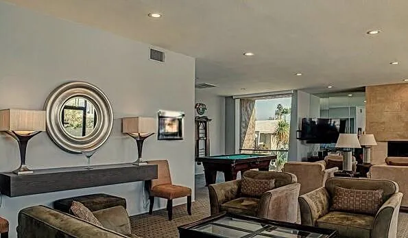 a living room with furniture a clock on wall and a mirror