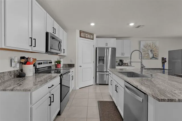 a kitchen with stainless steel appliances granite countertop a sink stove refrigerator and cabinets