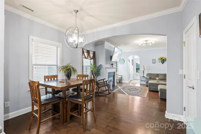 a kitchen with stainless steel appliances granite countertop a sink dishwasher a refrigerator a stove a dining table and chairs with wooden floor