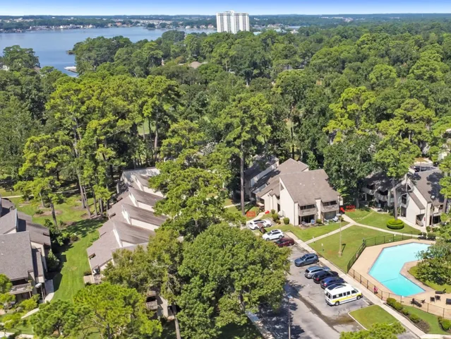 a view of swimming pool with lawn chairs and large trees