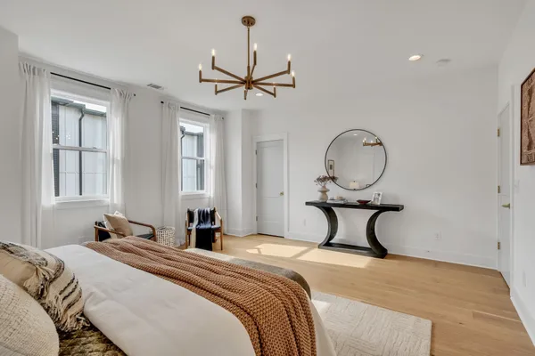 a bedroom with a bed large window with wooden floor