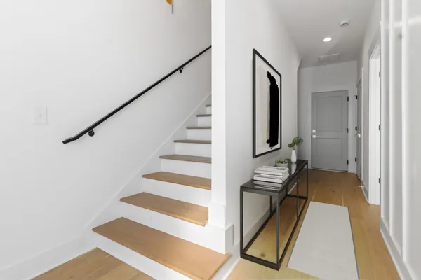 a view of a hallway with staircase and white walls
