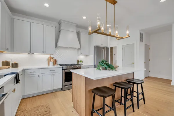a kitchen with stainless steel appliances a dining table chairs sink and cabinets