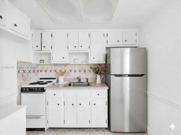 a kitchen with stainless steel appliances a refrigerator a stove and white cabinets