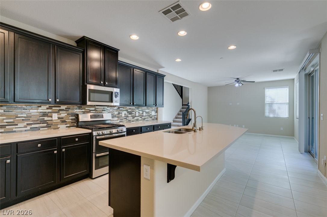 2549 Sable Ridge Street Henderson, NV 89044 - Photo 24 of 48 A streamlined kitchen layout with rich cabinetry, a quartz island, and modern stainless steel appliances.