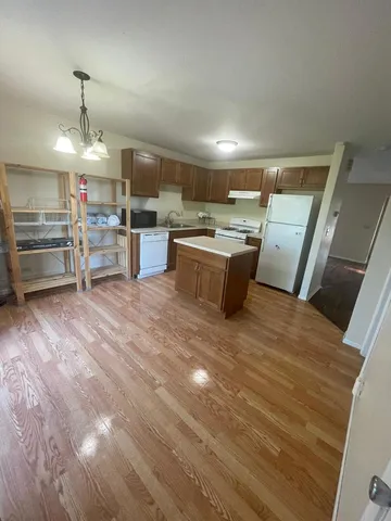 a large kitchen with a sink and dishwasher a stove top oven with wooden floor