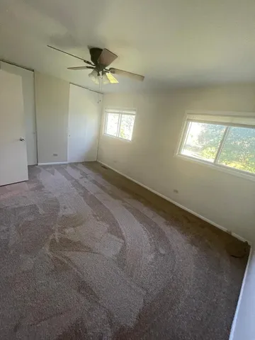 en empty room with windows and ceiling fan
