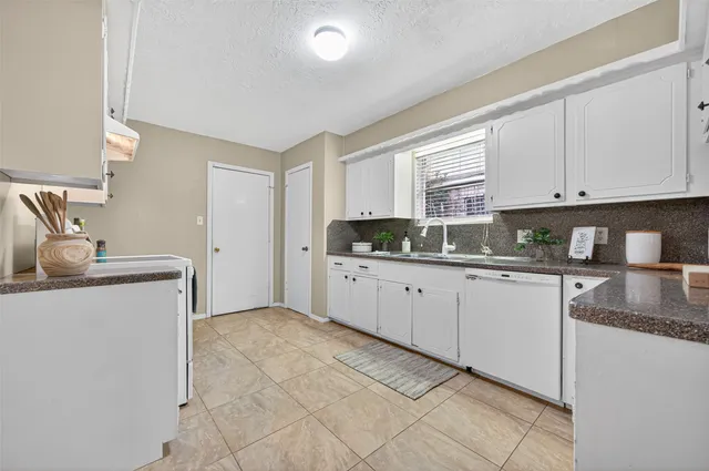 a kitchen with granite countertop a sink a stove and cabinets