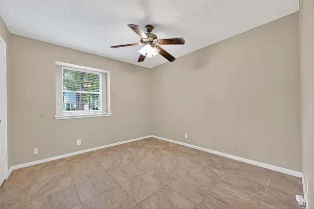 an empty room with windows and fan