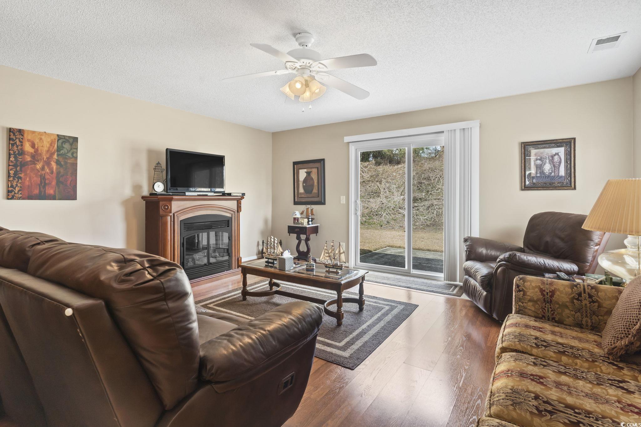 2288 Beauclair Court Myrtle Beach, SC 29579 - Photo 15 of 40 Living area featuring a textured ceiling, visible vents, wood finished floors, and a glass covered fireplace