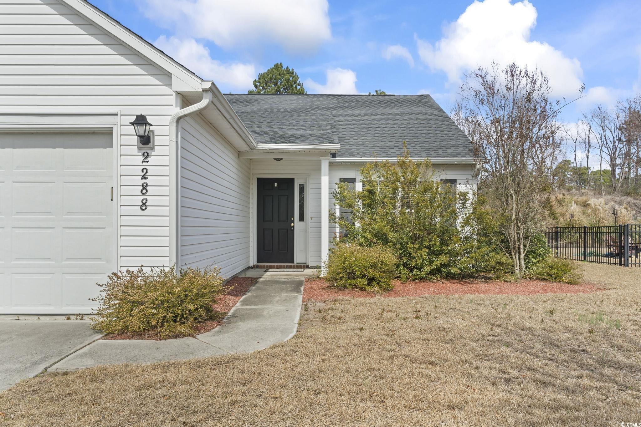 2288 Beauclair Court Myrtle Beach, SC 29579 - Photo 2 of 40 View of exterior entry featuring a shingled roof, a yard, fence, and a garage