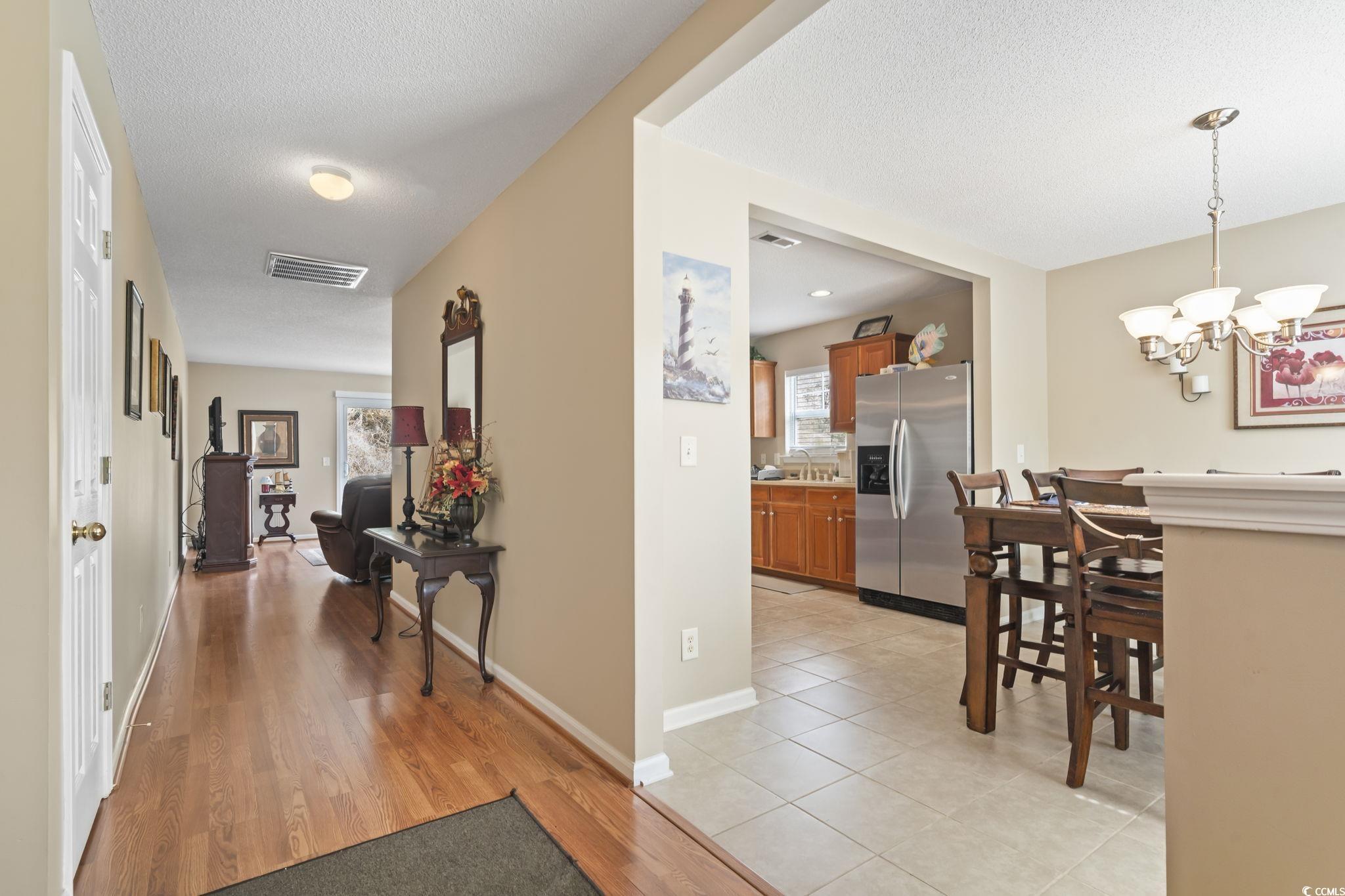 2288 Beauclair Court Myrtle Beach, SC 29579 - Photo 6 of 40 Corridor featuring a textured ceiling, a sink, visible vents, baseboards, and an inviting chandelier