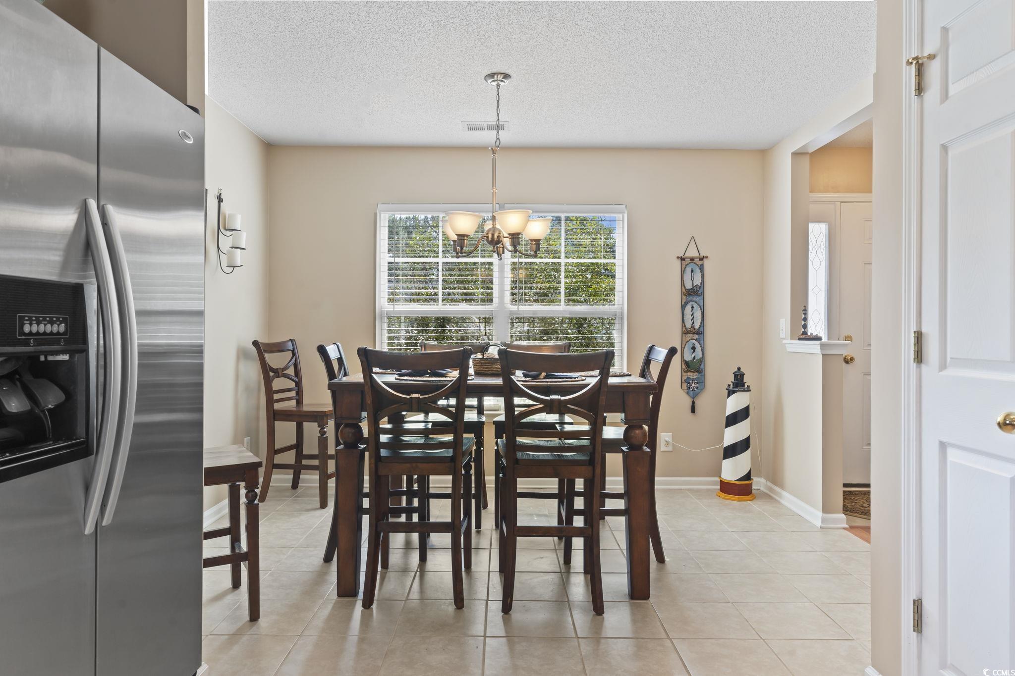 2288 Beauclair Court Myrtle Beach, SC 29579 - Photo 8 of 40 Dining room featuring a textured ceiling, light tile patterned flooring, baseboards, and a notable chandelier