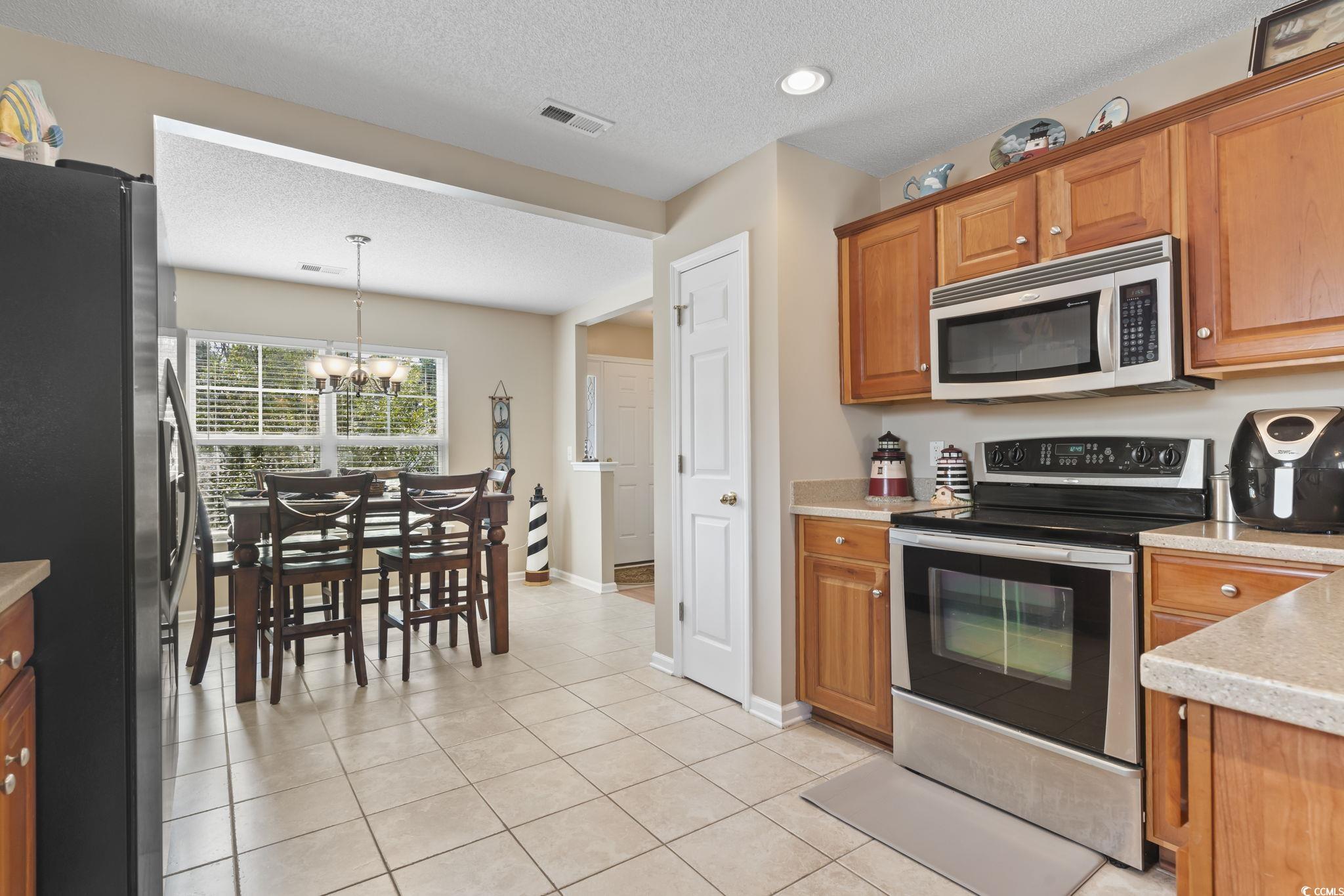2288 Beauclair Court Myrtle Beach, SC 29579 - Photo 9 of 40 Kitchen with appliances with stainless steel finishes, brown cabinets, light countertops, and light tile patterned flooring