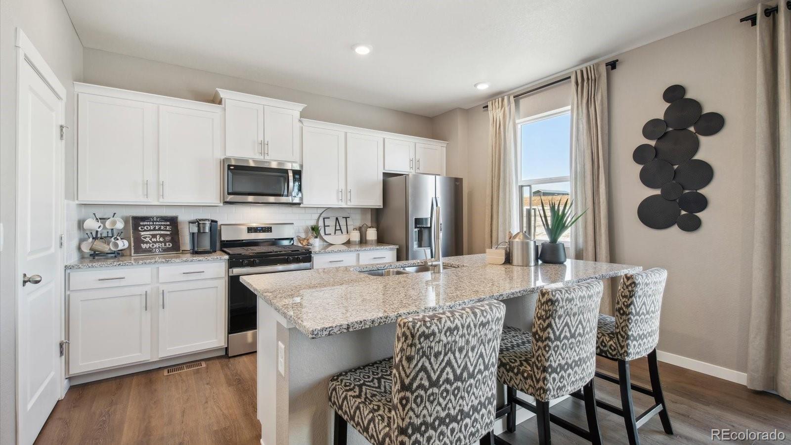 2202 Base Street Fort Lupton, CO 80621 - Photo 4 of 24 a kitchen with stainless steel appliances granite countertop a table chairs microwave and sink