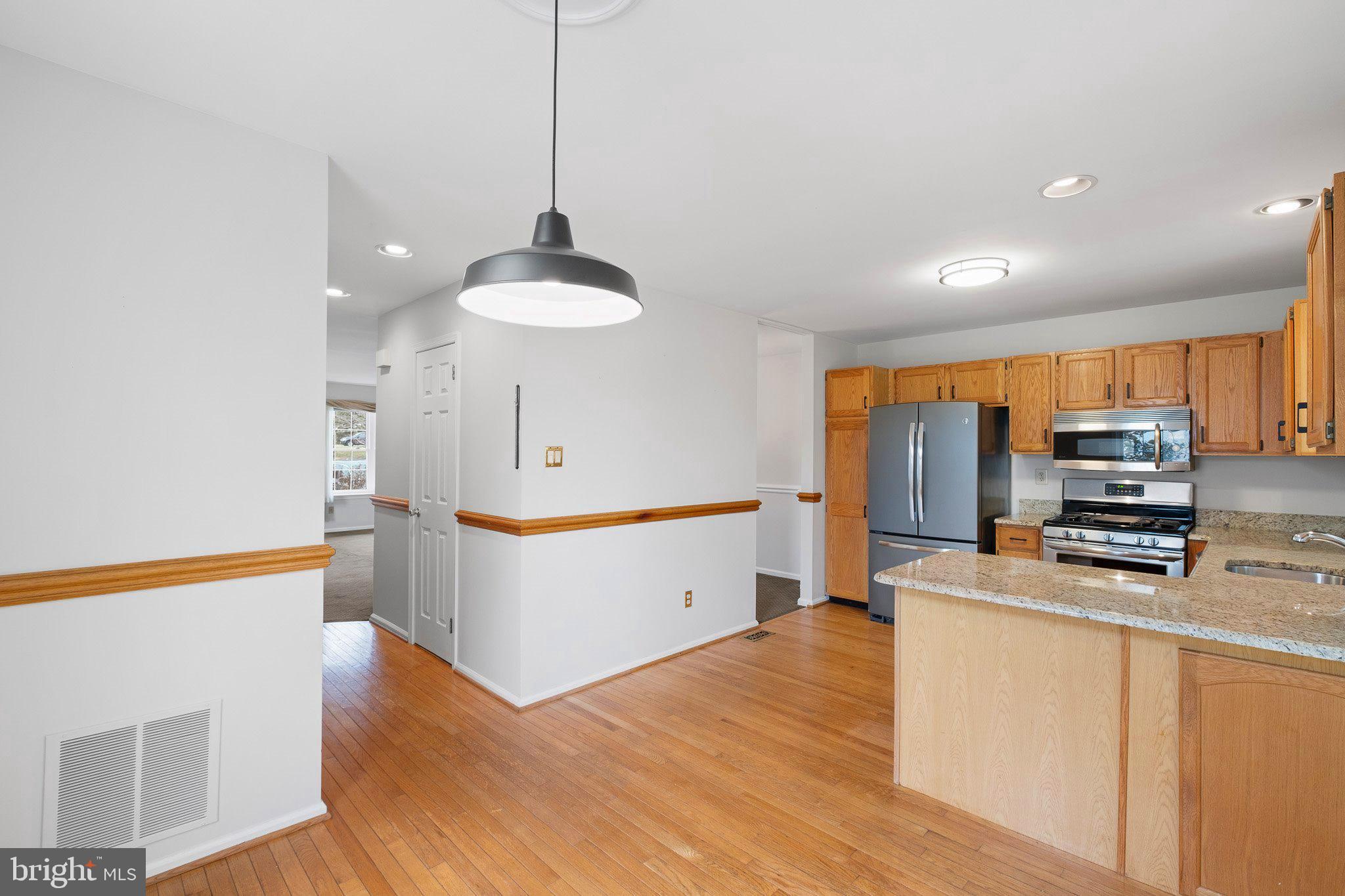 163 Cambridge Circle, Unit 78 Kennett Square, PA 19348 - Photo 7 of 30 a kitchen with stainless steel appliances a stove a sink a refrigerator a center island and wooden floor